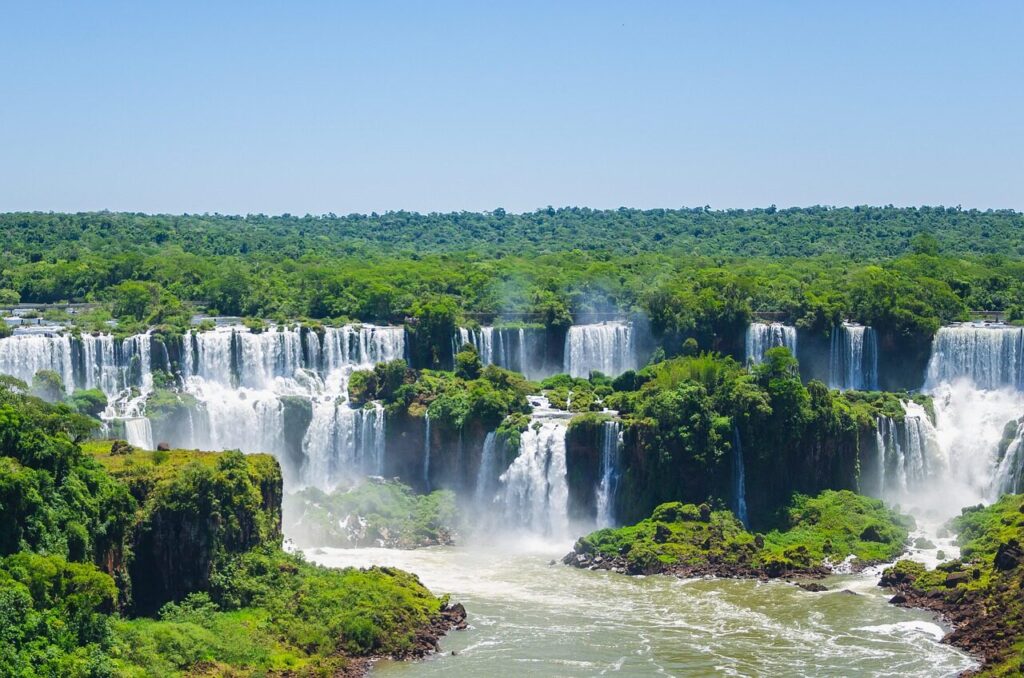 A rainbow over the cascades of Iguazu Falls surrounded by green rainforest
