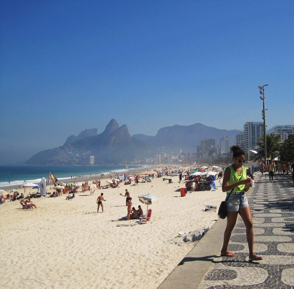Ipanema beach with sunbathers and the Dois Irmãos peaks rising behind the sand