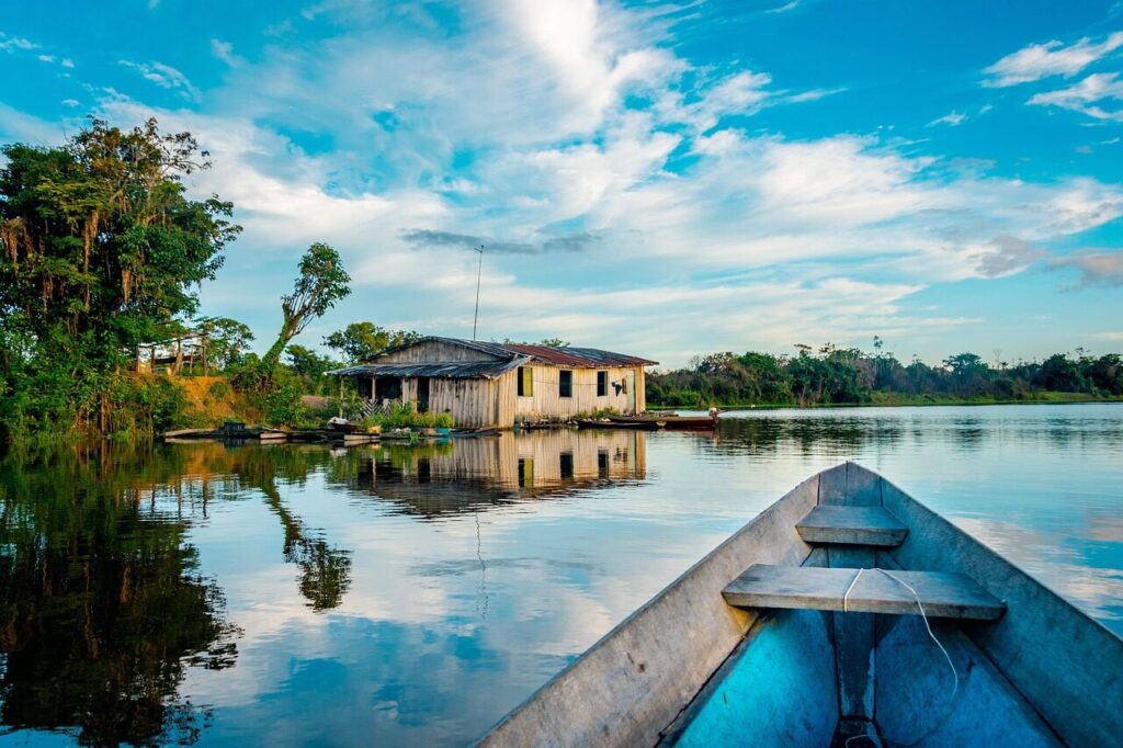 Small canoe on a dark Rio Negro channel surrounded by Amazon rainforest near Manaus
