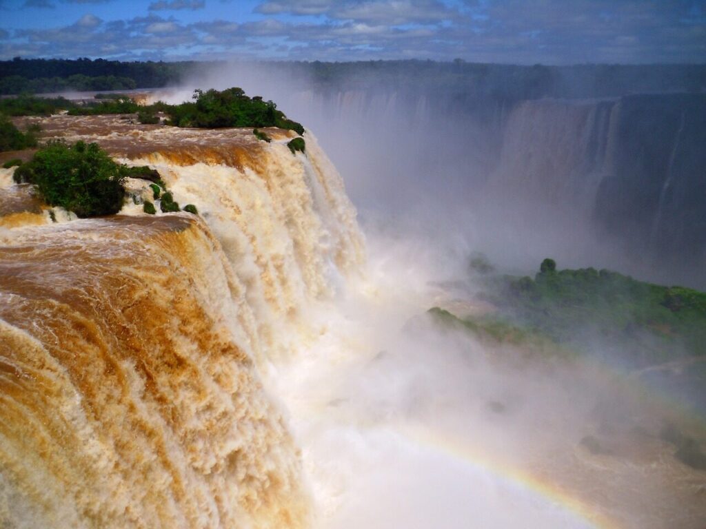 Water thundering into Devil's Throat at Iguazu Falls with mist rising above the walkway